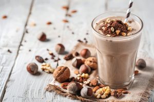 Chocolate milk cocoa with paper straw, decorated with chocolate powder and nuts